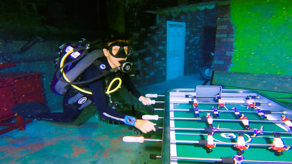 A scuba woman playing foosball at Deep Dive Dubai