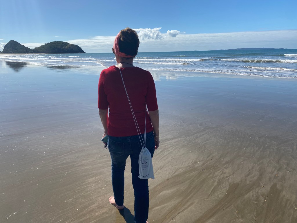 A Scuba Woman walking on the beach with a Moon Reusable Water Bottle