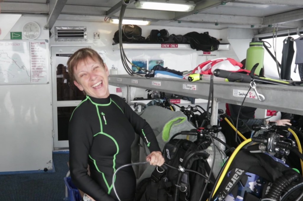 A Scuba Woman laughing with dive gear on a boat