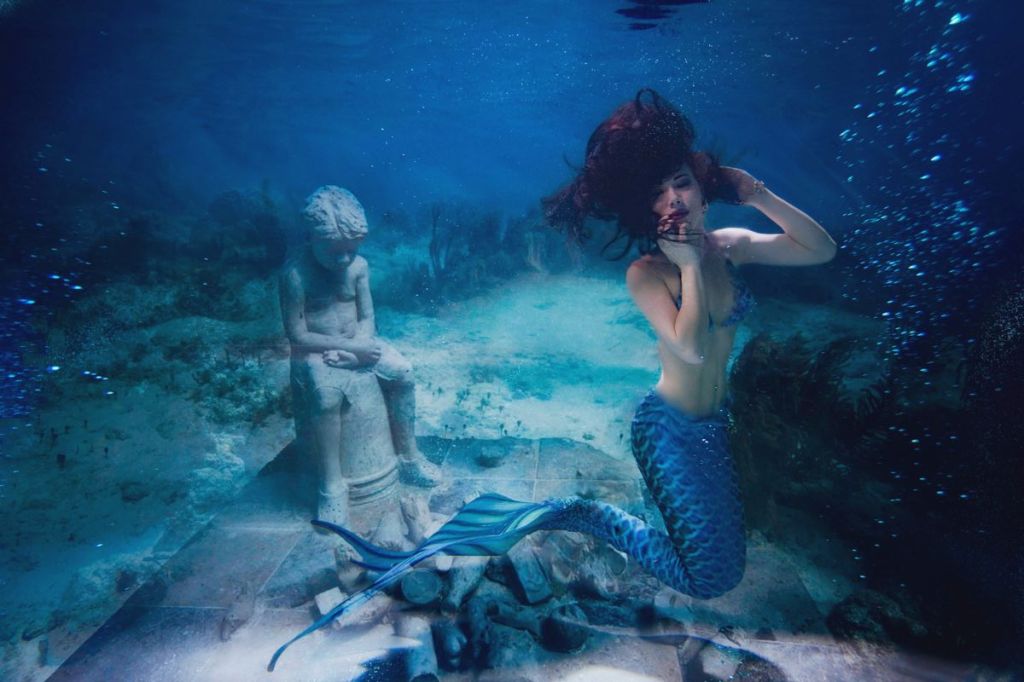 A mermaid and a statue underwater
