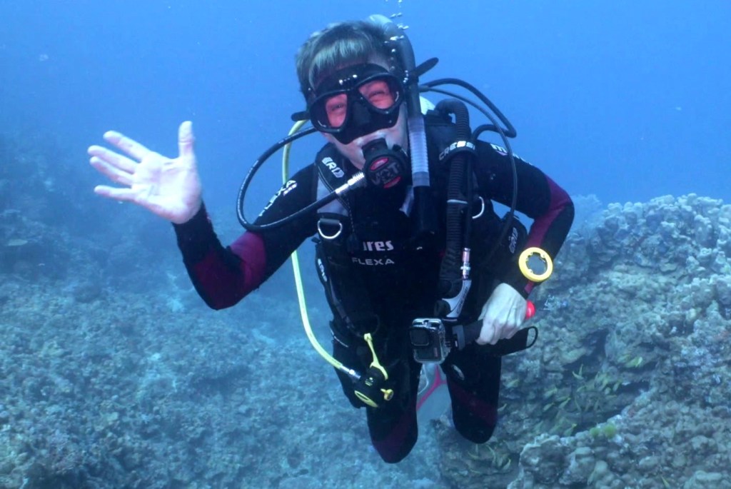 A Scuba Woman Smiling and waving underwater
Empty Nest Diver